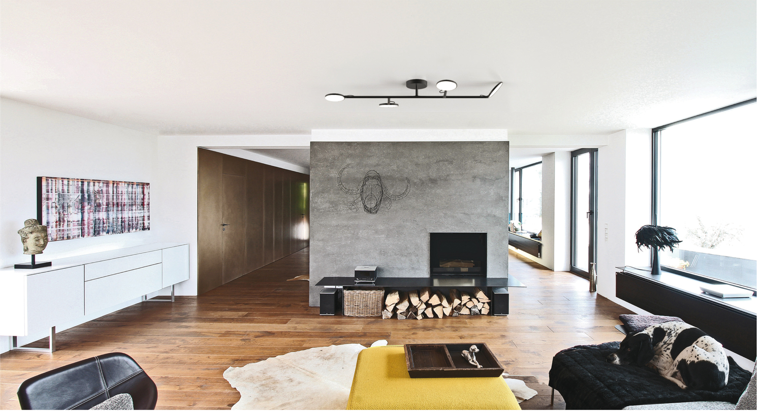 4-branched black ceiling light ending in 4 round flat light heads, AVVENI CEILING 4, above a living room table.