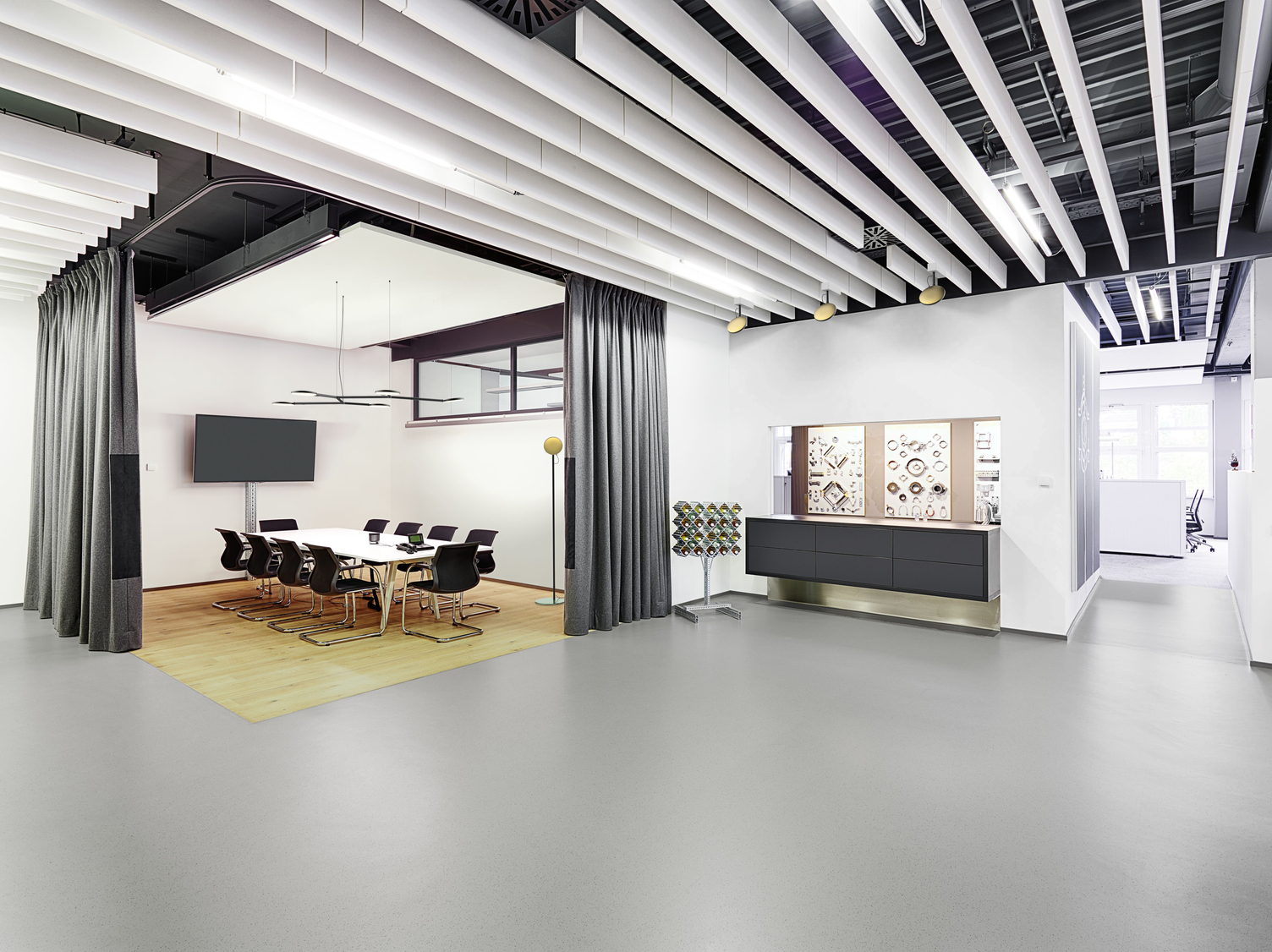 Open office space, in a meeting room separated by curtains hangs a black branched luminaire with round light heads of AVVENI Pendant 5 - Type 3, next to the table stands a floor lamp with a golden round luminaire head.