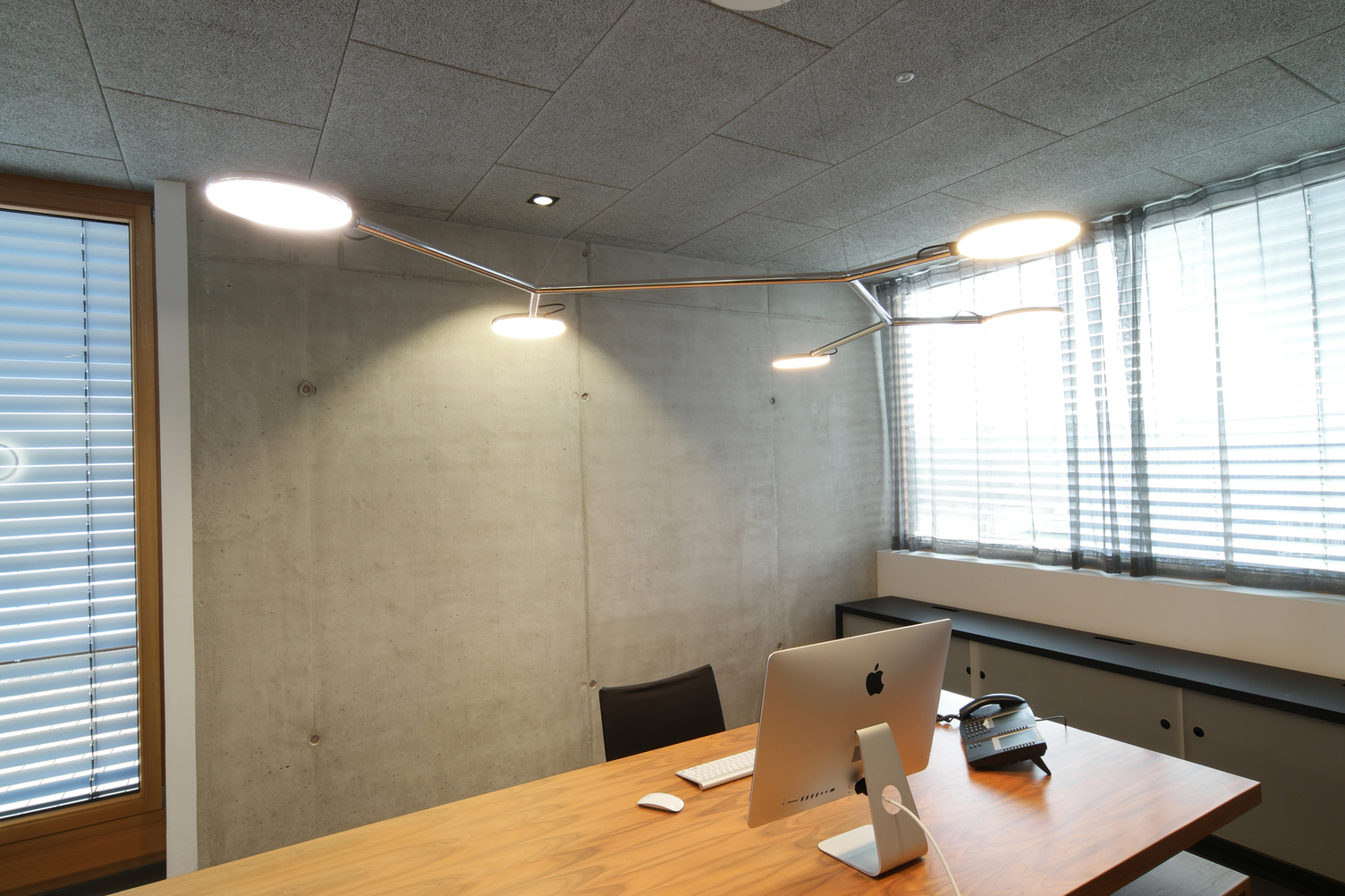 Pendant light for the modern office Branched luminaire made of polished aluminium with 5 movable flat, round luminaire heads, AVVENI Pendant 5 Type 3, suspended above a modern office desk.