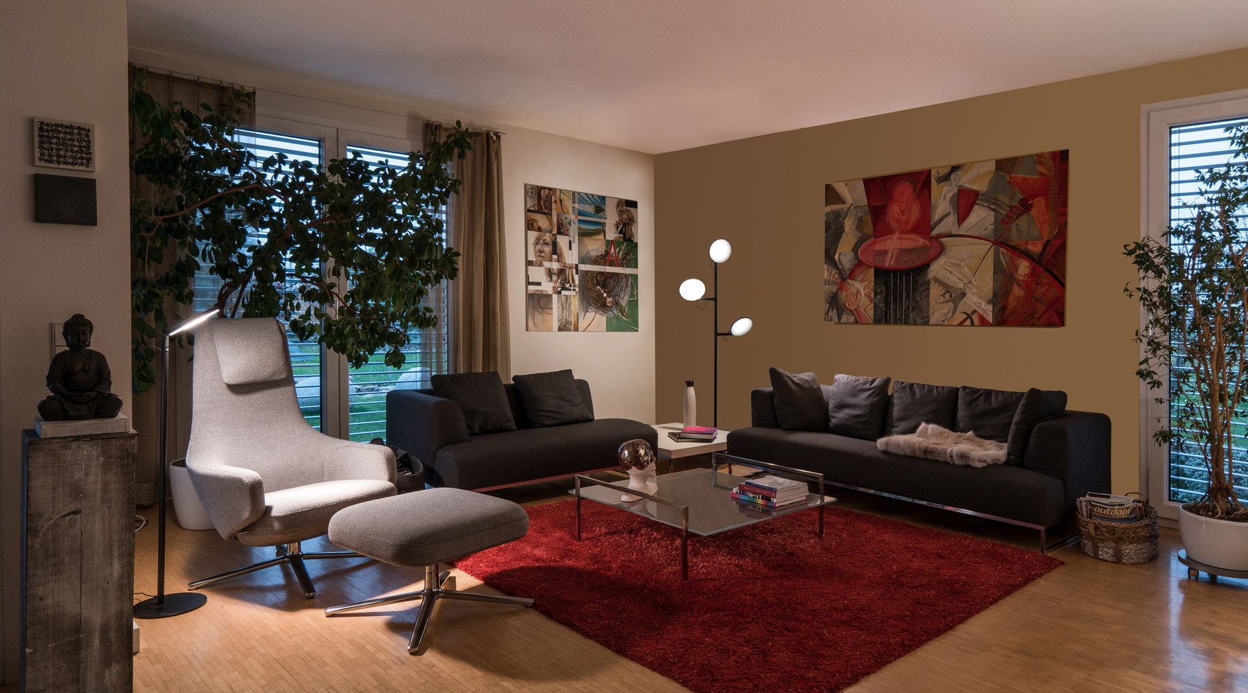 Wohnzimmerlandschaft mit verschiedenen Dekorativen Elementen und einer Stehleuchte mit einem Kopf neben Sessel und einer Stehleuchte mit drei Köpfen zwischen zwei grauen Sofas.