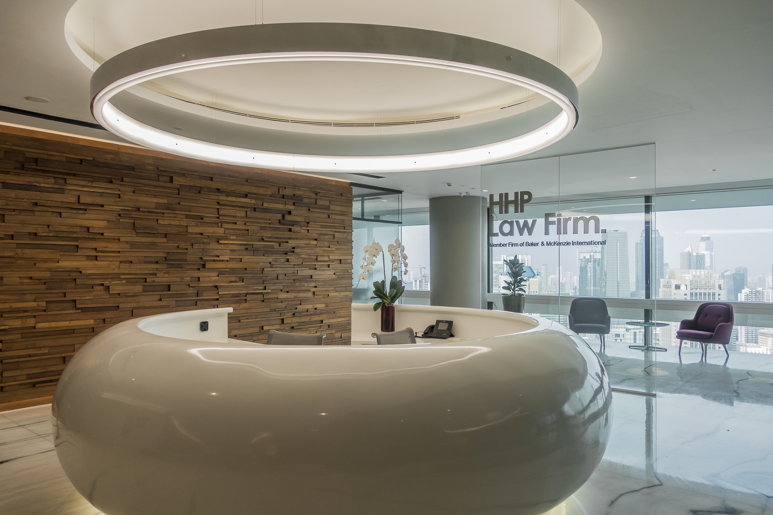 Runde Aluminium polierte Ringleuchte mit L-Diffusor über runder Empfangstheke.