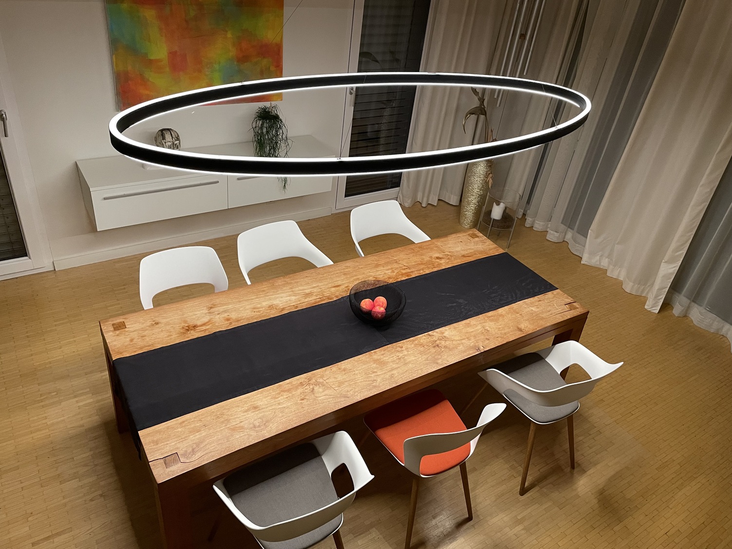Elliptische Ringleuchte DOPPIO ELLIPSE über rechteckigem Esstisch Elliptische Ringleuchte Doppio Ellipse direkt und indirekt leuchtend über modernen Esszimmer-Holztisch.