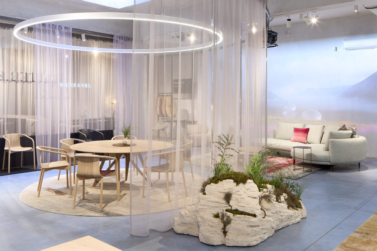 Messestand mit Wolkenwänden, Vorhängen und zentral im Fokus durch eine runde Ringleuchte (DUETTO) in Szene gesetzt ist eine Esstischgruppe mit Stühlen von WALTER KNOLL.