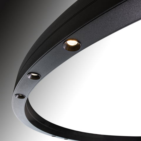 Round lenses arranged in groups Detail of a black ring light, DUETTO LENS, three round luminous lenses are visible, directly illuminated in the centre of the ring profile.