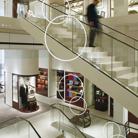 GIRATA VERTICAL luminaire ensemble for stairwells Three pairs of two ring luminaires from the GIRATA VERTICAL luminaire series are suspended in pairs at different heights in the stairwell of a department store, filling the stairwell.