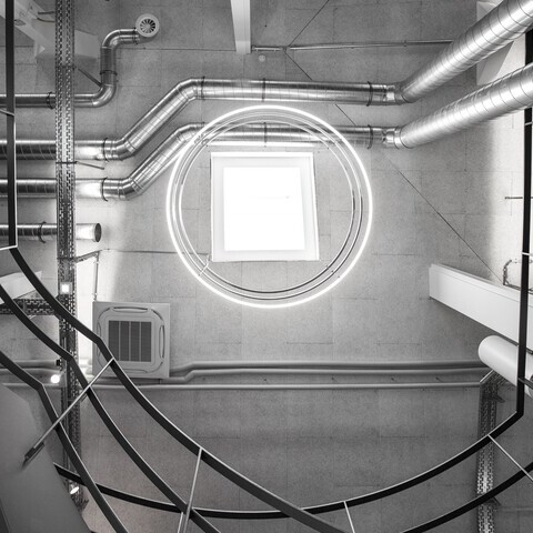 INSIEME chandelier in the stairwell of an industrial-style building View from below in a stairwell of a concrete industrial building of madness GmbH to the ceiling of 3 INSIEME ring lights suspended one below the other.