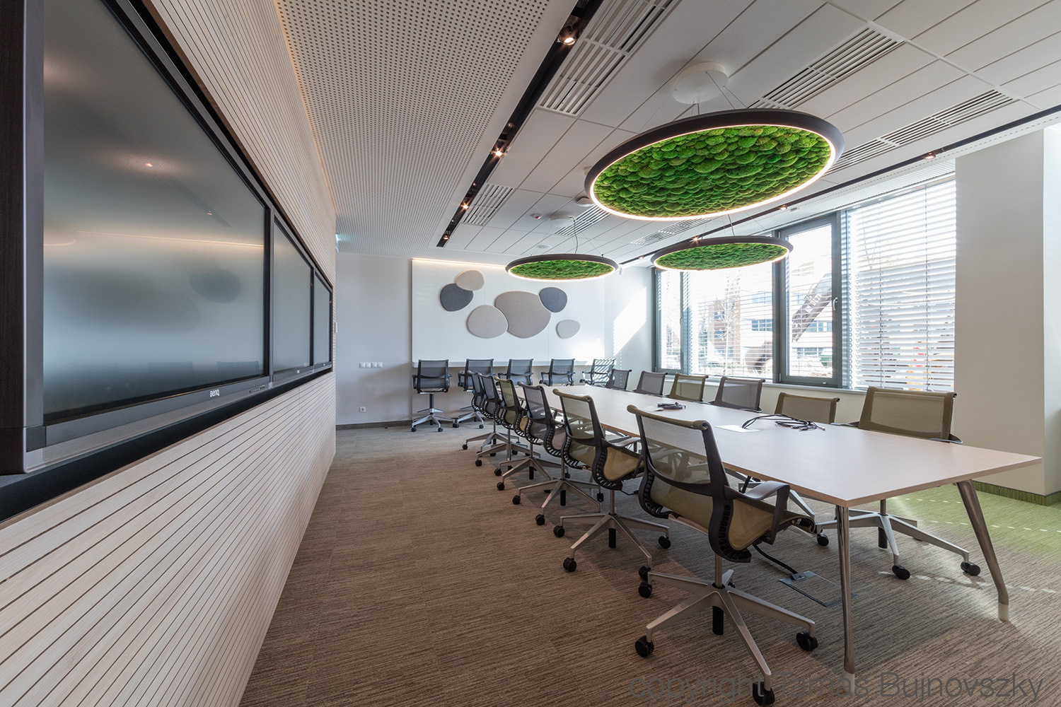 SAP Office Budapest – Acoustic Ceiling Solutions & Modern Lighting Innovative meeting room with green acoustic panels, natural lighting, and ergonomic furniture.