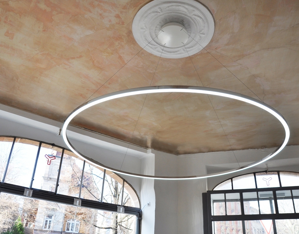 Optional: current carrying suspension Slender ring pendant luminaire (SLIM DIRECT) attached to a canopy on a stucco ceiling. The luminaire appears to float in the room due to the thin current-carrying suspension.