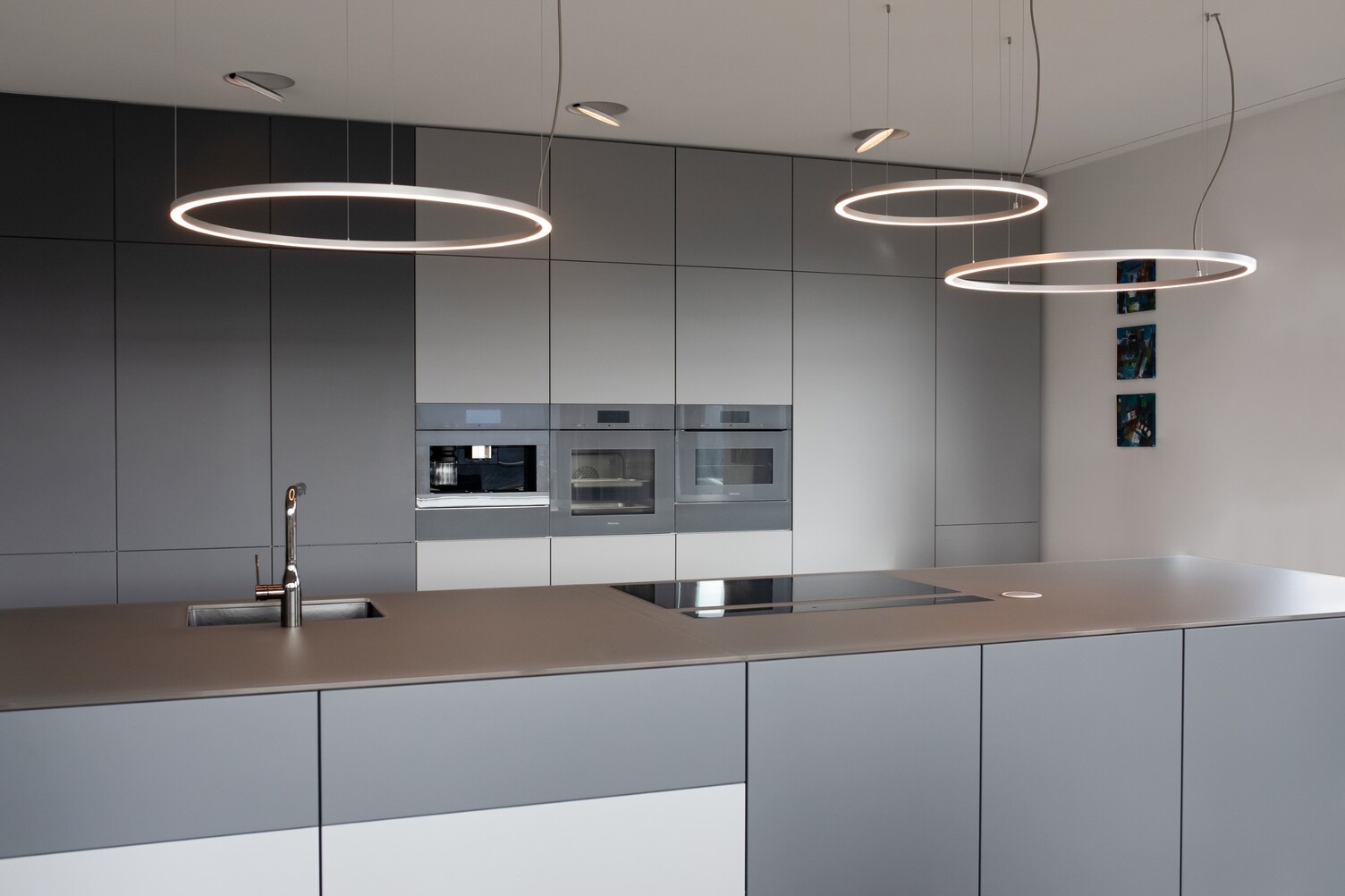 Three SLIM DIRECT Ring Lights in Aluminium above Kitchen Counter – Modern Residential Interior Three filigree SLIM DIRECT LED ring luminaires by SATTLER in brushed aluminium above a kitchen counter, providing direct lighting for a modern private kitchen.