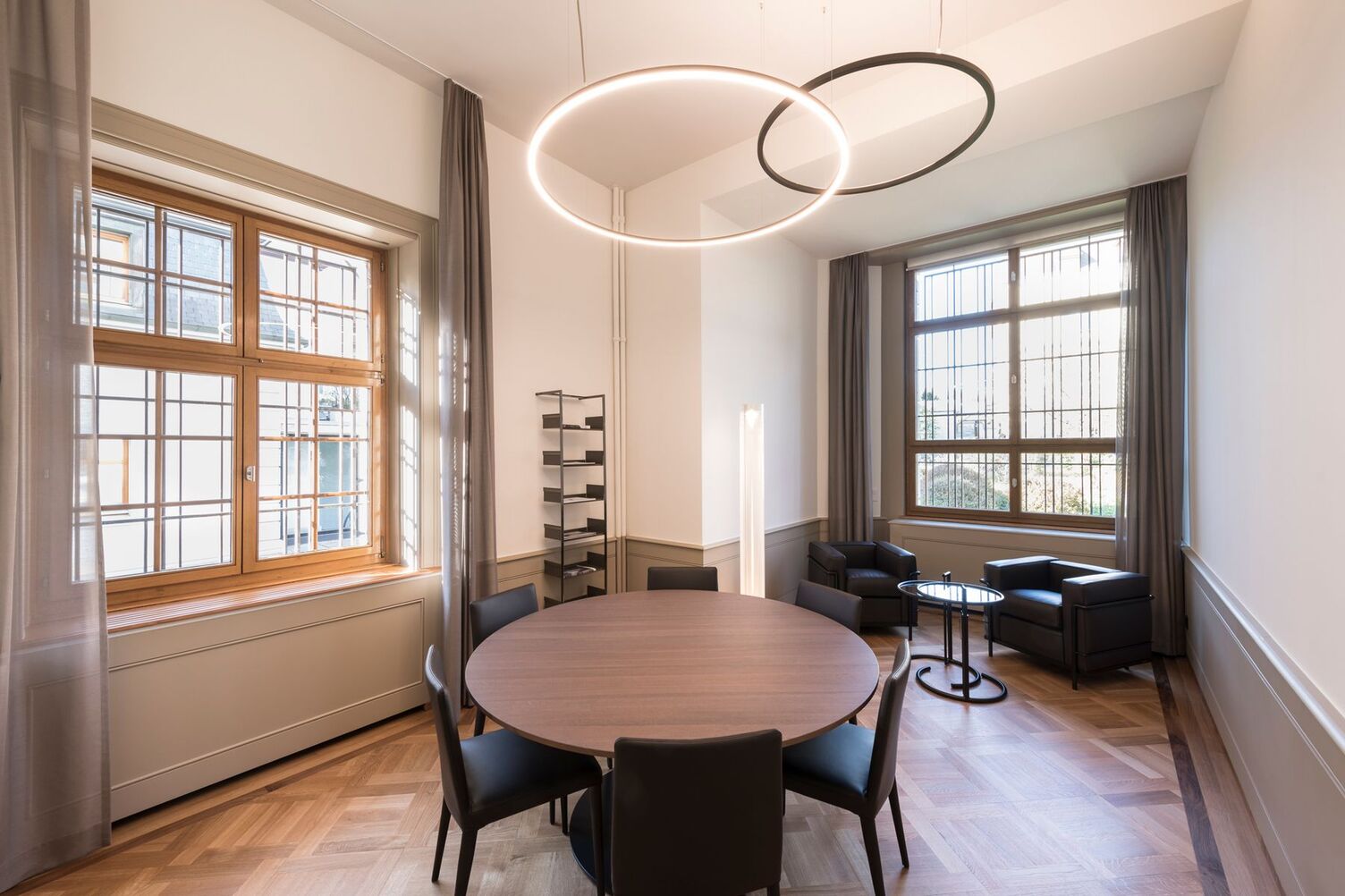 Round meeting island in a meeting room with Slim direct above and Slim indirect in satin bronze in a historic bank building