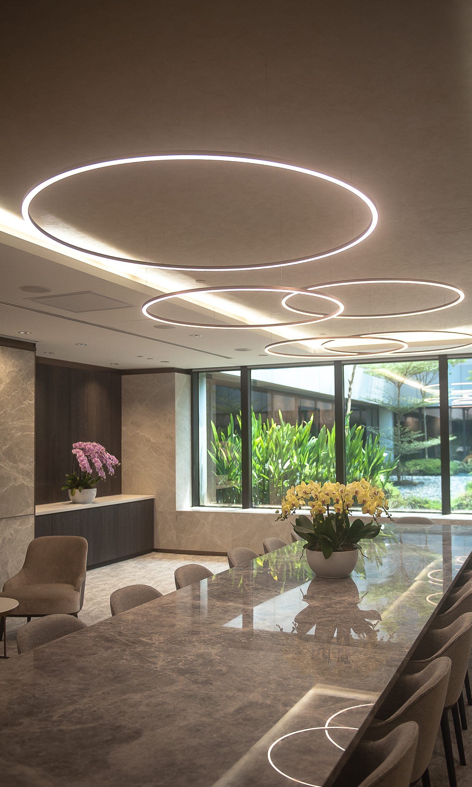 SLIM DIRECT Ring Lights in Special Bronze Varnish above Marble Table – Changi Airport Five filigree SLIM DIRECT LED ring lights in Special Bronze Varnish by SATTLER suspended above a premium marble table at Changi Airport, providing direct illumination with refined architectural presence.