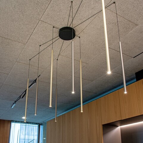 SOLUZIONE + 8 x FINO PENDANT Round ceiling canopy (black) from which 8 cables run out in a star shape to a small round ceiling bracket. The cables are suspended downwards and terminate in cylindrical, narrow pendant lights, FINO PENDANT with various surface colours, gold, aluminium, polished aluminium.