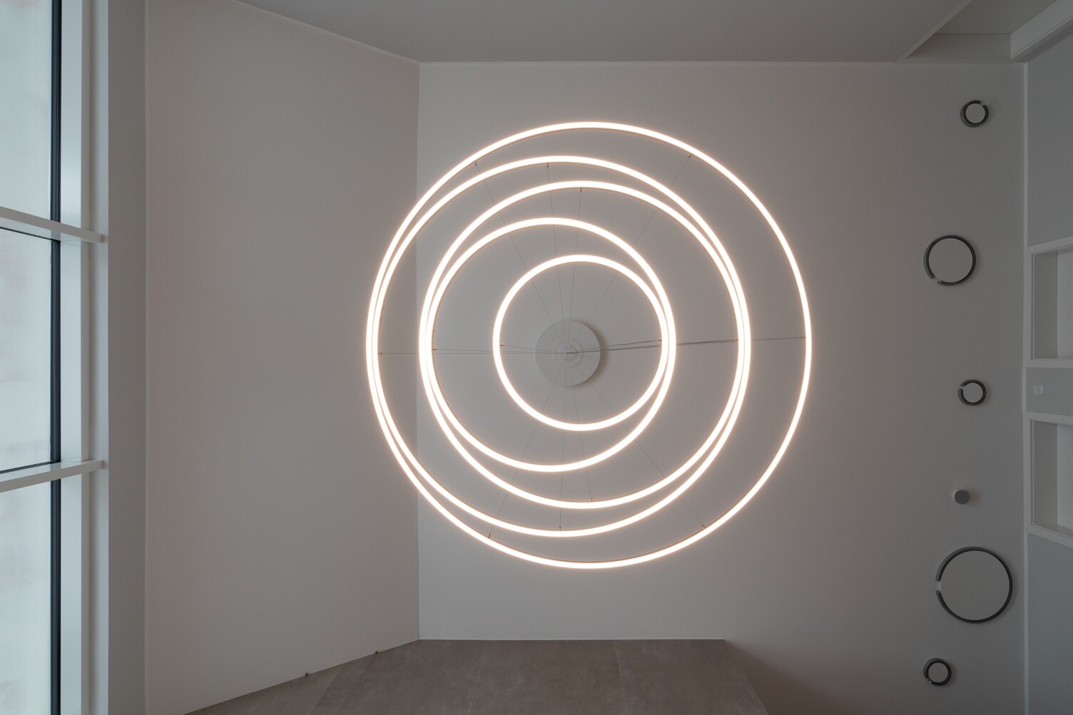 Lichtringfaszination TOCCATA Blick von unten an die Decke auf einen modernen Kronleuchter bestehend aus mehreren Lichtringen, der eine Spiralform ergibt: die Pendelleuchte TOCCATA 1900.