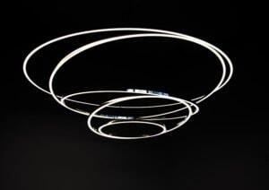 TOCCATA ring light object - spiral, staggered, beautifully shaped Black background on which the TOCCATA ring light consisting of 5 narrow aluminium ring profiles, the largest at the top and the smallest at the bottom, are always connected at one point.