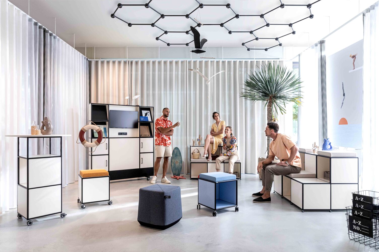 Contemporary showroom with modular furniture and Favo Cell lighting fixture by Sattler in Offenbach, featuring a relaxed group discussion.