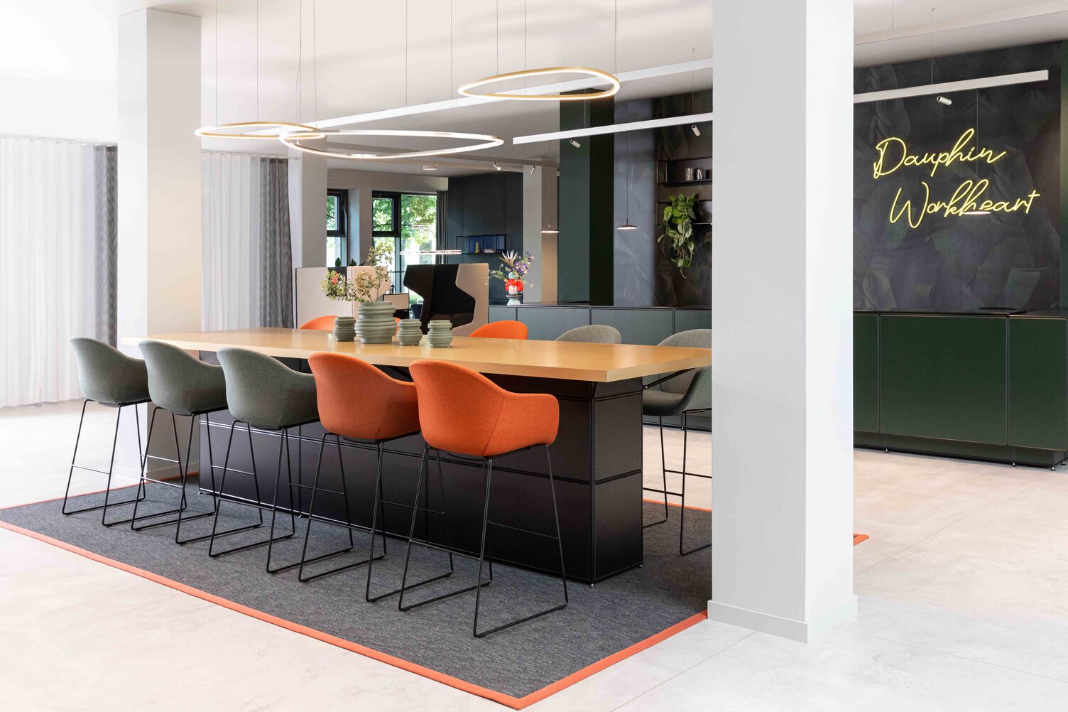 Slim Delta Direct luminaires from SATTLER on a conference counter Meeting point with Slim Delta Direct luminaires from SATTLER. In the background, a reception desk with Paladio System Track luminaire and Paladio System LENS, each installed as a pendant version at different heights. Avveni Pendant 1 and Evo Spot were also used in the Track luminaire