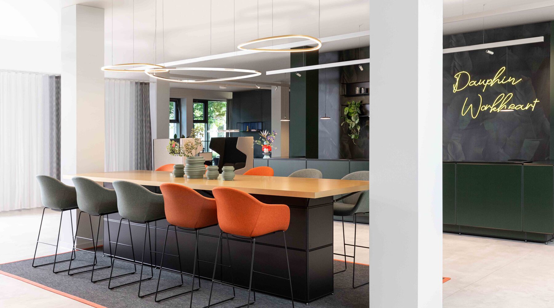 Slim Delta Direct luminaires from SATTLER on a conference counter Meeting point with Slim Delta Direct luminaires from SATTLER. In the background, a reception desk with Paladio System Track luminaire and Paladio System LENS, each installed as a pendant version at different heights. Avveni Pendant 1 and Evo Spot were also used in the Track luminaire