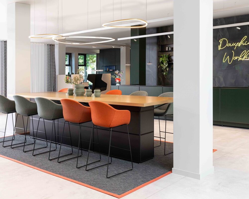 Slim Delta Direct luminaires from SATTLER on a conference counter Meeting point with Slim Delta Direct luminaires from SATTLER. In the background, a reception desk with Paladio System Track luminaire and Paladio System LENS, each installed as a pendant version at different heights. Avveni Pendant 1 and Evo Spot were also used in the Track luminaire