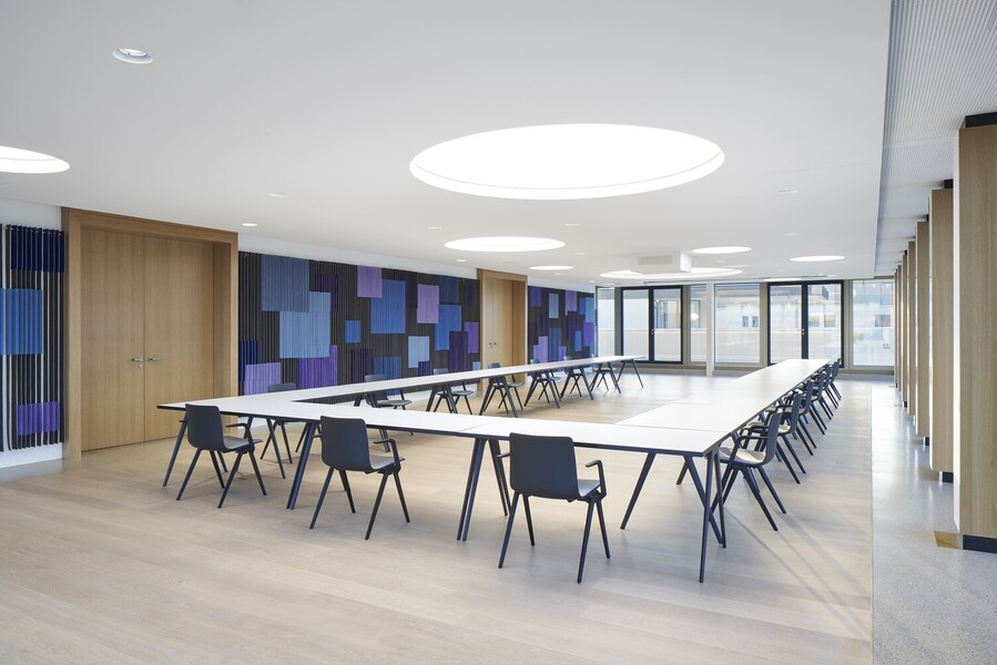 Modern conference room with round light ceilings Conference room with a large U-shaped arrangement of tables, the walls are graphically designed in shades of blue, round light ceilings are distributed around the room in the white ceiling.