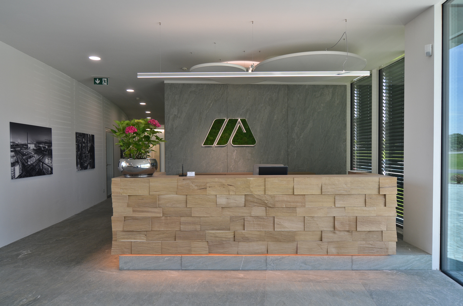 SATTLER Doppio Linea in polished aluminium in combination with acoustic panel and Moos special luminaires Logo | © SATTLER | Werbe-und Medienagentur Mohring Reception desk with a Doppio Linea in polished aluminium. In the background there are additional acoustic panels, as well as a moss light as a special version of the company logo on the wall, all from SATTLER. | © SATTLER | Werbe-und Medienagentur Mohring