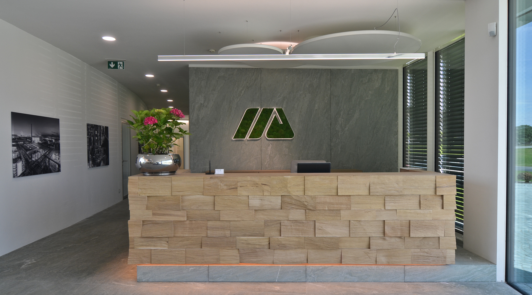 SATTLER Doppio Linea in polished aluminium in combination with acoustic panel and Moos special luminaires Logo | © SATTLER | Werbe-und Medienagentur Mohring Reception desk with a Doppio Linea in polished aluminium. In the background there are additional acoustic panels, as well as a moss light as a special version of the company logo on the wall, all from SATTLER. | © SATTLER | Werbe-und Medienagentur Mohring