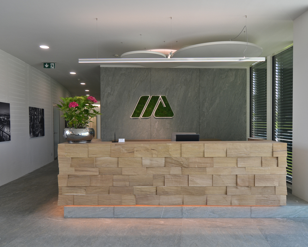 SATTLER Doppio Linea in polished aluminium in combination with acoustic panel and Moos special luminaires Logo | © SATTLER | Werbe-und Medienagentur Mohring Reception desk with a Doppio Linea in polished aluminium. In the background there are additional acoustic panels, as well as a moss light as a special version of the company logo on the wall, all from SATTLER. | © SATTLER | Werbe-und Medienagentur Mohring