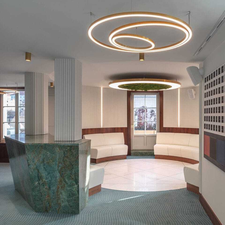 Reception area in the Postpalast, Budapest, with green marble and Sattler's Toccata 900 lighting fixtures with Luce Verde Anello.
