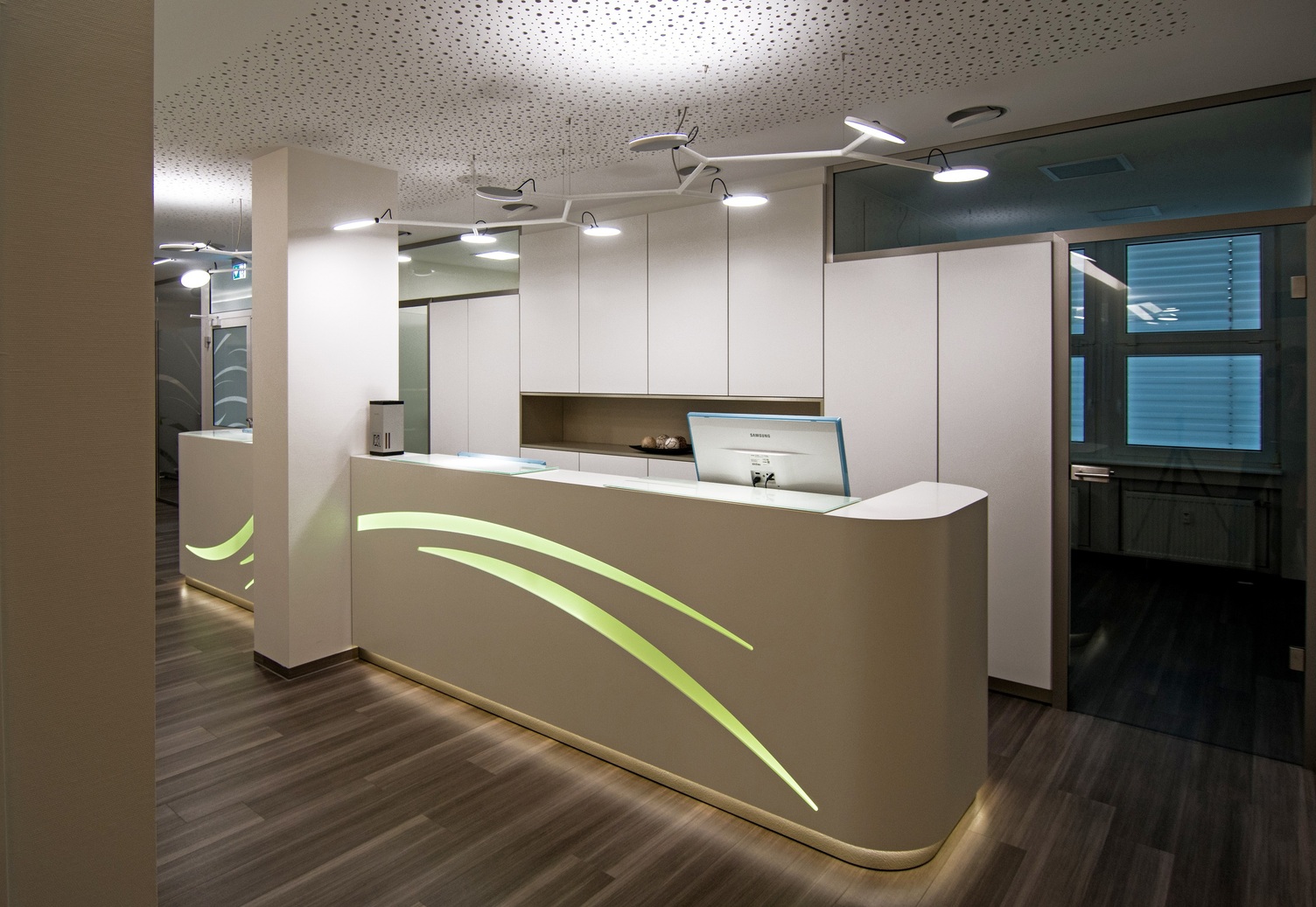 Linear branched pendant light AVVENI PENDANT 8 above the reception desk Reception desk at Dr. Bernas' practice with AVVENI PENDANT