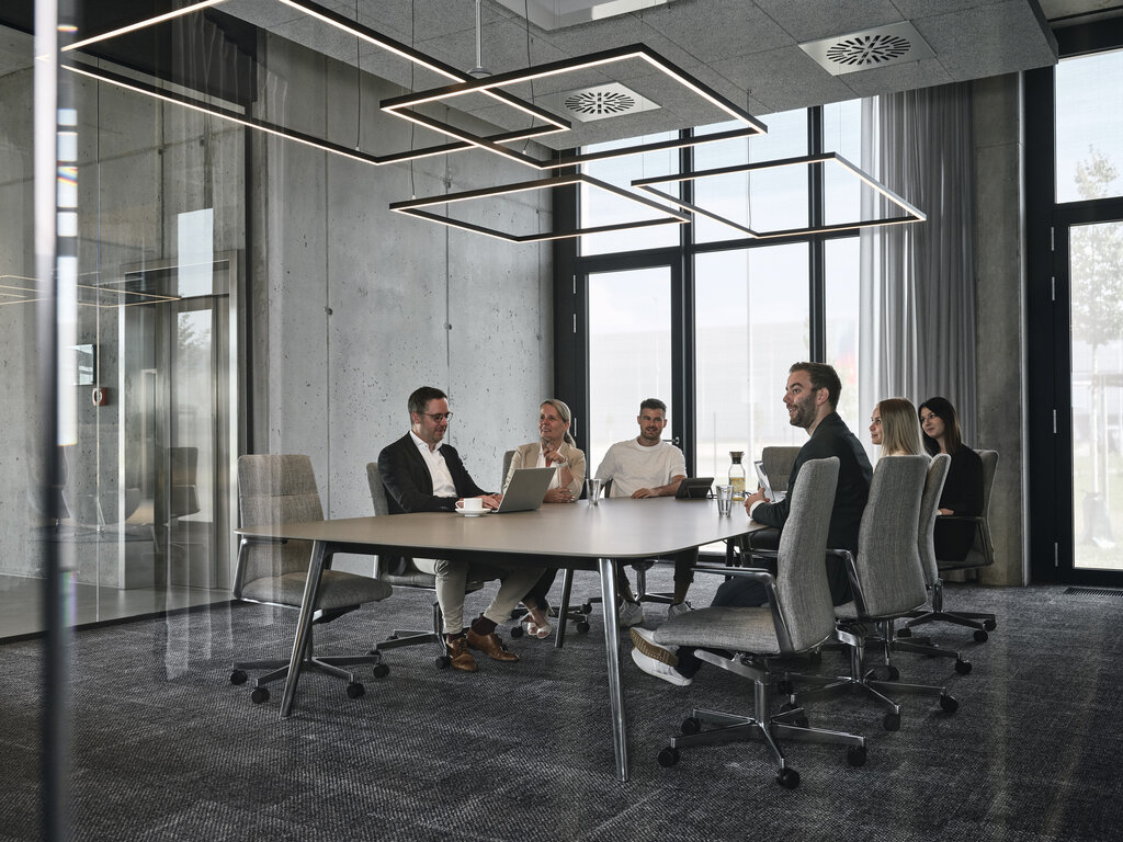 Modern meeting room at Streit, featuring concrete walls and Sattler's Gioco lighting fixtures  under an acoustically effective suspended ceiling.  | © Christoph-Duepper