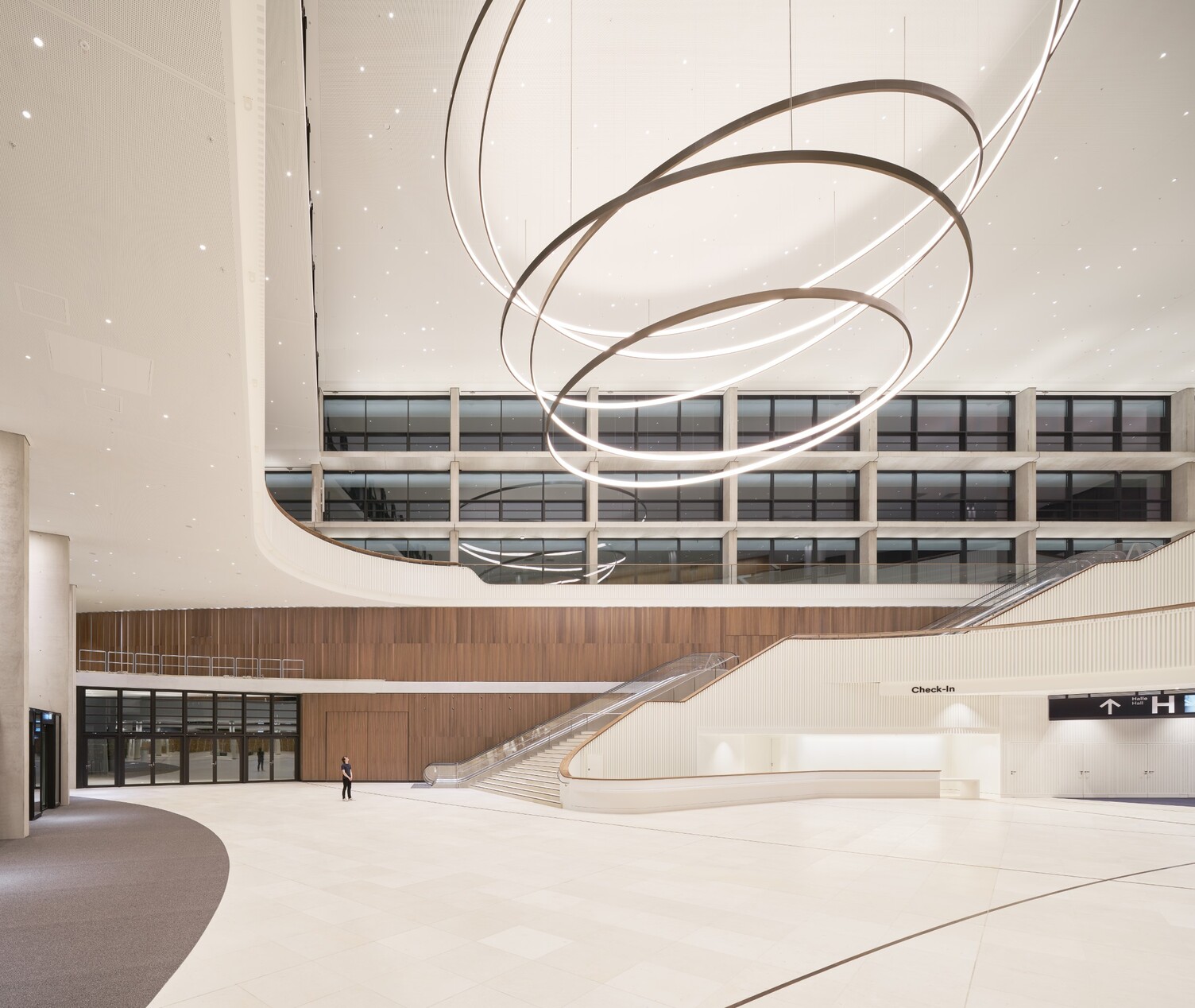 Huge spiral luminaire - CCH Hamburg A person stands in the entrance area of the CCH Hamburg and looks up at a room-filling spiral luminaire.