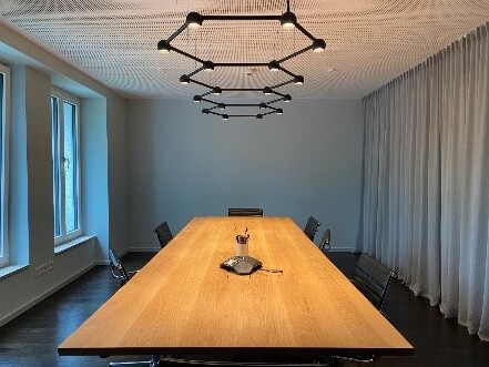 Dr. Satzl, Munich – Geometric Ceiling Lights for Modern Meeting Rooms Exclusive meeting room with geometric black ceiling lights and a high-quality wooden table.