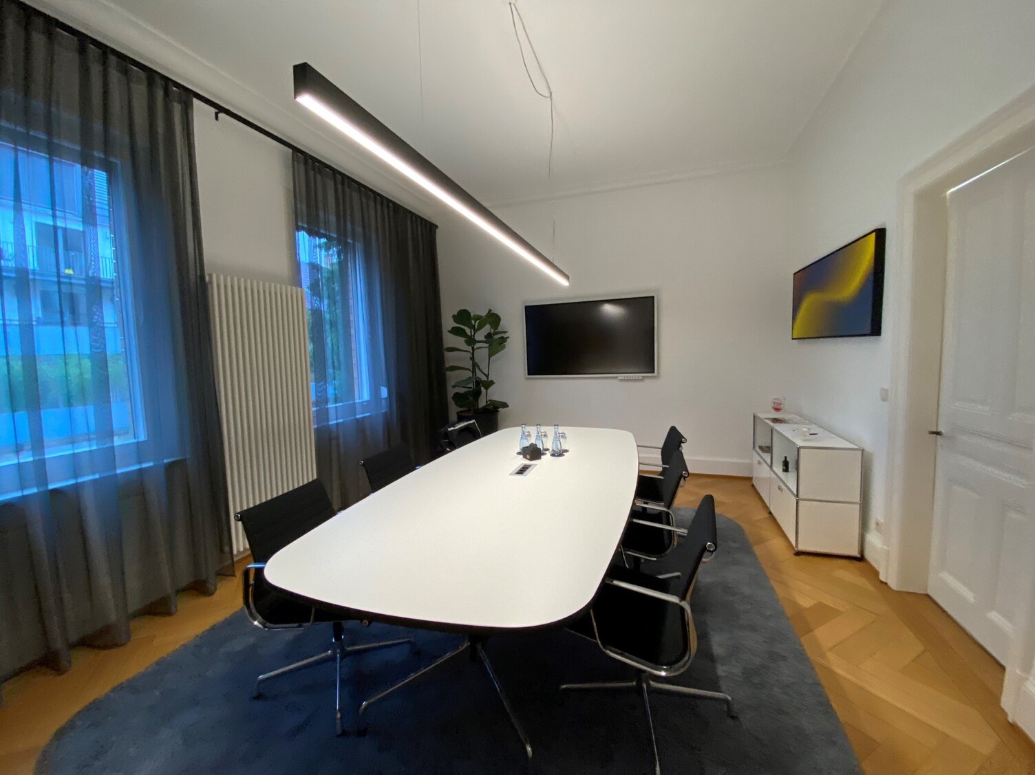 Steuerkanzlei Matussek – Meeting Room with Pendant Light Meeting room Steuerkanzlei Matussek with linear pendant light above conference table, dark curtains